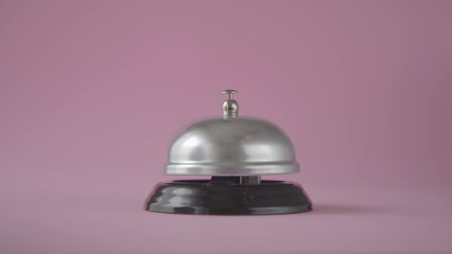 Hand ringing in service bell on a pink background