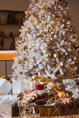 festive table. New Year's and Christmas. tangerines, sweets, garlands and gifts under the tree. white tree and golden balls