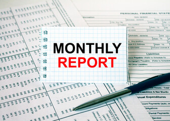 Fototapeta premium Notepad with text Monthly Report lying on financial tables with a pen