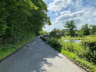 View along, Neps Lane, with an old stone bridge, that spans the River Ribble in, Newsholme, Clitheroe, UK