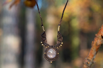 Mineral rose quartz gemstone ornamental pendant on blury forest background
