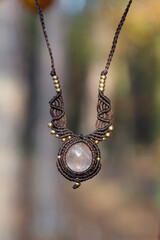 Mineral rose quartz gemstone ornamental pendant on blury forest background