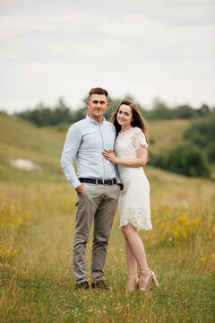 Young beautiful couple is hugging in the field in summer. woman with long hair and man with stylish haircut