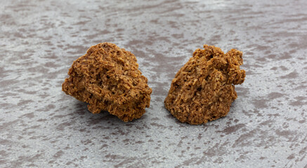 Side view of two gluten free chocolate macaroons on a gray background.