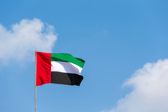 Flag waving in the sky, national symbol of United Arab Emirates. National Day and UAE flag day concept.