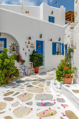 Picturesque alley in Prodromos Paros greek island with whitewashed traditional houses with blue door  and flowers all over.