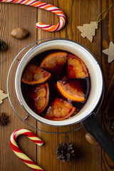 top view of freshly cooked mulled wine with orange slices in a saucepan, grog or punch or other hot...