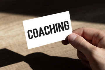 Businessman holding in hand a card with text COACHING