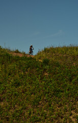 A lone mountain biker disappearing over a hill on a jeep track