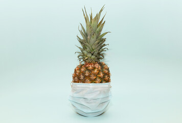 Ripe pineapple in a medical mask on a blue background.