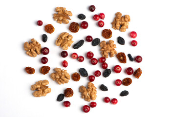 Dried cranberries, walnuts, raisins, on white paper background.