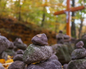 cross behind rocks in autumn forest