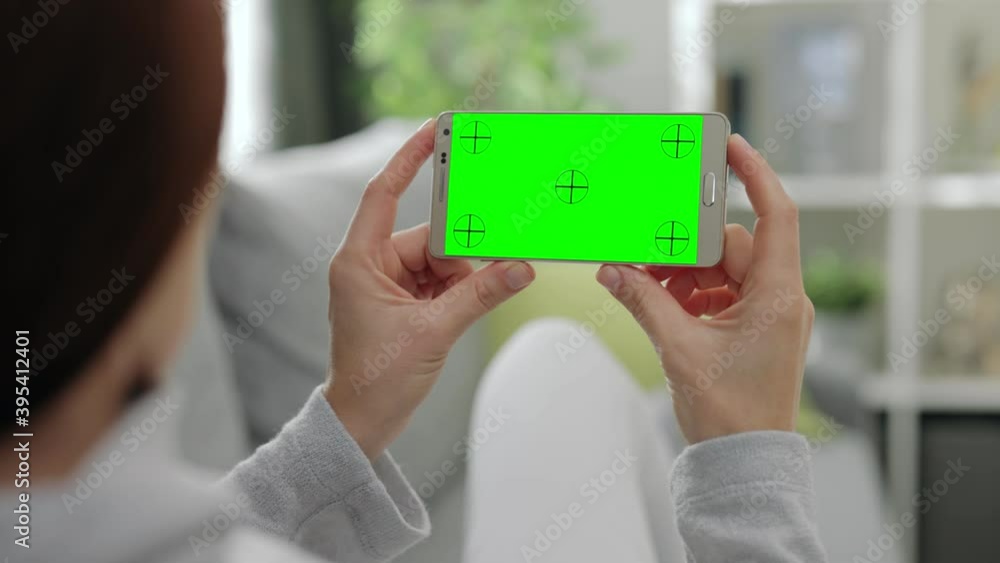 Poster back view of woman enjoying leisure time at home and using smartphone with chroma key screen. young 