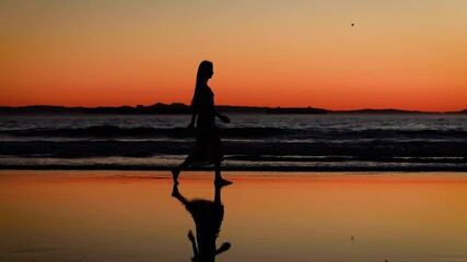 Pretty Asian woman enjoys a walk on the beach at sunset. Slow Motion.