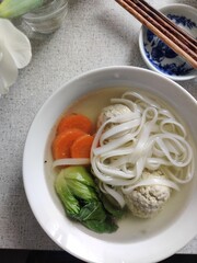 Asian cuisine: soup with meatballs, carrots, rice noodles, bok choy