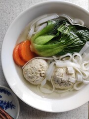 Asian cuisine: soup with meatballs, carrots, rice noodles, bok choy