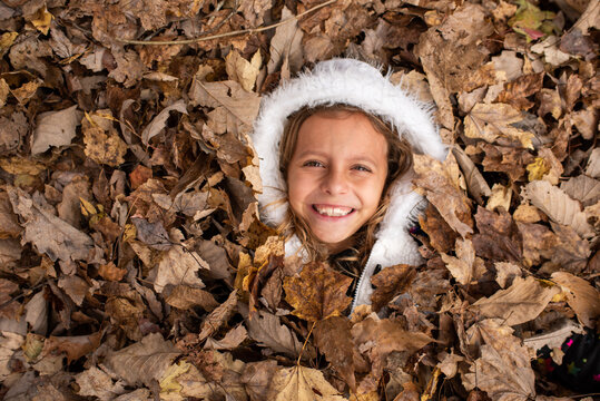 Little girl having fun in a pile of leaves
