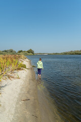 The girl is standing in the water. The girl stands in the water near the beach.