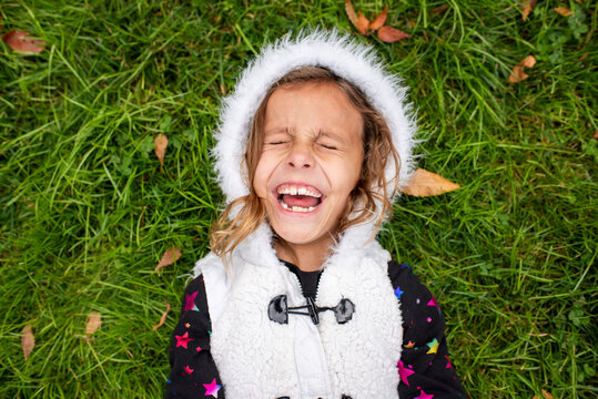 Young girl laughing on green grass