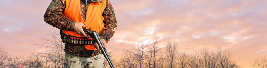 Silhouette of a hunter with a gun against the sun, an ambush for ducks.