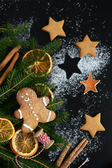 Dark christmas background with snowflakes, spices, candy cane, fir tree and gingerbread cookies. Copy space for text.