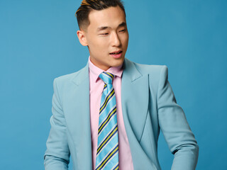 Asian businessman in suit on blue background looking to the side cropped view