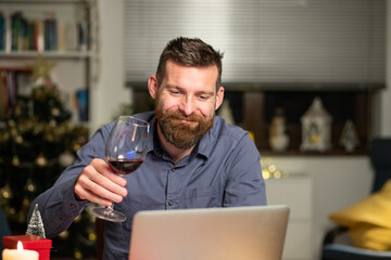 portrait of handsome man spending Christmas eve at home with laptop