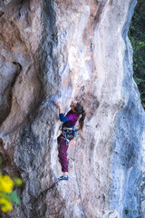 Fototapeta premium A strong woman climbs a rock, Rock climbing in Turkey.