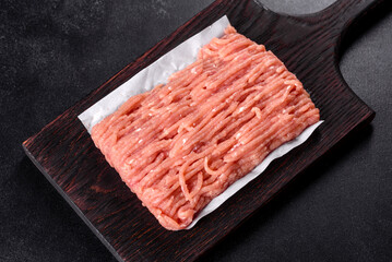 Fresh raw chicken mince on a dark wooden cutting board