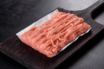 Fresh raw chicken mince on a dark wooden cutting board