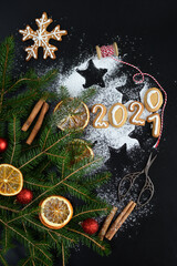 Dark christmas background with snowflakes, spices, candy cane, fir tree and gingerbread cookies. Gingerbread cookies numbers 2021.Festive Winter Holidays concept.Copy space for text.