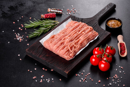 Fresh raw chicken mince on a dark wooden cutting board