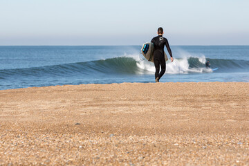 Young man with surf board walking on the beach