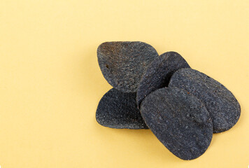 Black potato chips on yellow background. Texture and background. Close up.