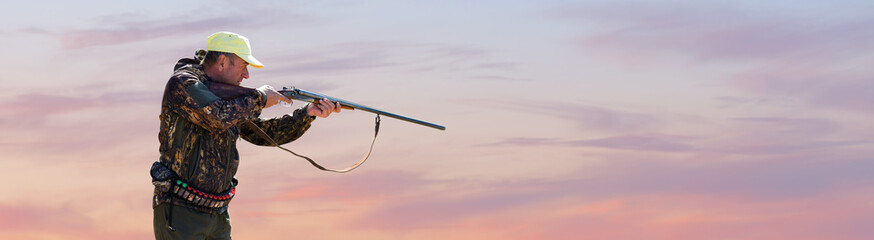 Silhouette of a hunter with a gun against the sun, an ambush for ducks.