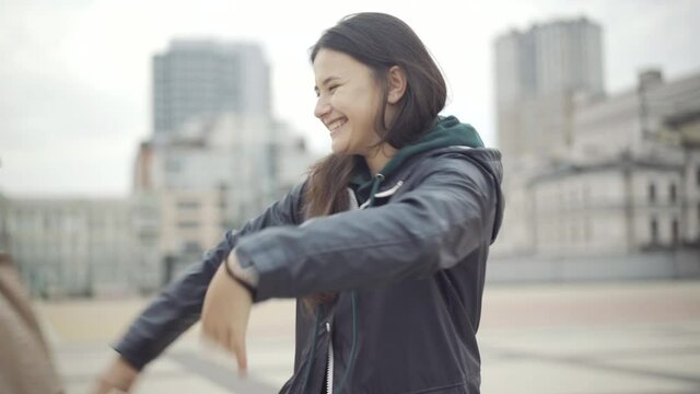 Portrait of young beautiful woman checking time on watch, crossing hands and sighing. Brunette charming Caucasian lady meeting friend on city square, smiling and leaving. Friendship concept.
