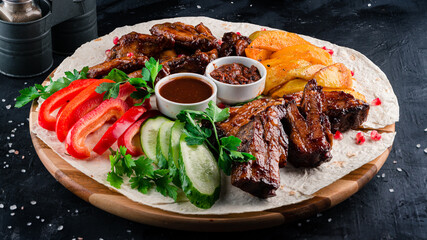grilled chicken wings and grilled ribs BBK on a round wooden Board