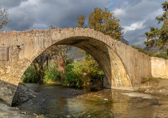 Fototapeta na wymiar The beautiful arched bridge of Prevelis crossing the Megas River which empties at the famous beach of Preveli. Built in the 18th century by monks of the Prelevi, Southern Crete, Greece