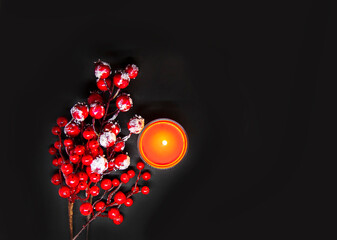 Festive Christmas or New Year composition with red holly berries in snow and burning wax candle