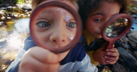 Small boy and girl looking at camera with magnifying glass
