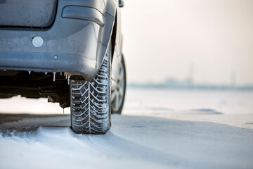 Close up of a car tire parked on snowy road on winter day. Transportation and safety concept.