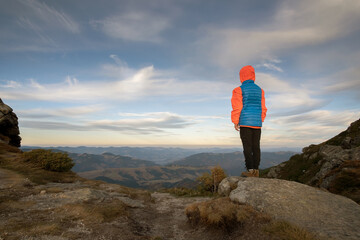 Obraz premium Young child boy hiker standing in mountains enjoying view of amazing mountain landscape.
