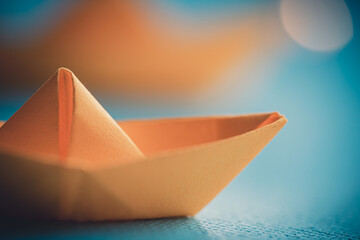 Origami yellow sailing boat on a sea made with blue paper. Paper art style background with ship,...