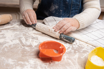 Knead flour dough on a wooden table, top view, children's hands. Home cooking for the family. Chef at workplace in the kitchen. Making dough. Healthy delicious recipe.