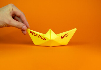 Image of businessman pushing paper made origami boat forward in a conceptual image. Words 'relation...