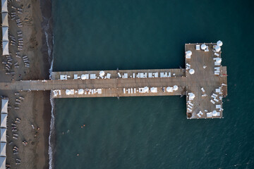 Resort coast with wooden pier in the sea, aerial view. Drone view over transparent blue water,...