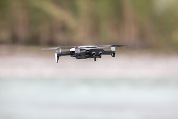 Drone with professional cinema camera flying over a blue calm river in the forests