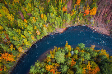 Gorgeous look down travel aerial of red dirt cliffs and fall foliage leaves on deciduous trees and...