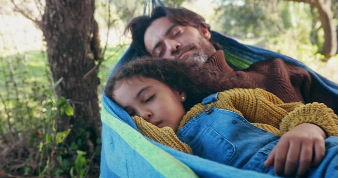 Father and daughter sleeping on a hammock in the woods