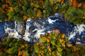 Beautiful look down travel photograph of the upper Potato River Falls waterfall cascades and whitewater rapids cutting through the deciduous and evergreen forest wilderness in Wisconsin.
